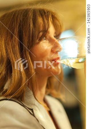 Woman sipping wine at social gathering Woman sipping wine at social gathering 142865903