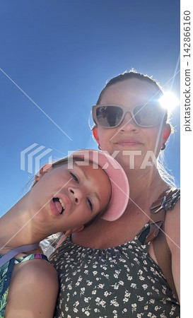 Happy mother and daughter taking silly selfie on sunny summer vacation. 142866160