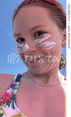Teenager girl applying facial sunscreen protection for melanoma and sunburn prevention. Teenager girl applying facial sunscreen protection for melanoma and sunburn prevention. 142866162