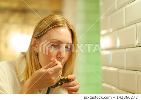 Woman eating oyster in restaurant Woman eating oyster in restaurant 142866278