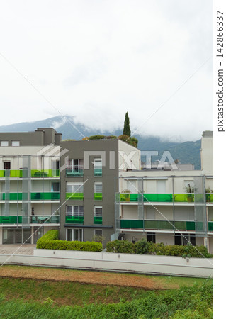 Modern apartment building with mountain backdrop Modern apartment building with mountain backdrop 142866337