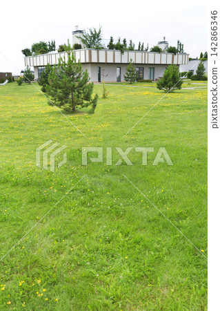 Modern eco building with green roof on sunny lawn. Creative sustainable resort architecture landscaping design. Peaceful summer park garden hospitality nature background. 142866346