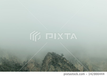 Misty mountain peaks shrouded in fog Misty mountain peaks shrouded in fog 142866444