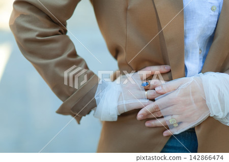 Close up of person in brown blazer with jewelry 142866474