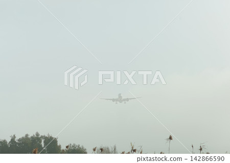 Airplane approaching through fog Airplane approaching through fog 142866590