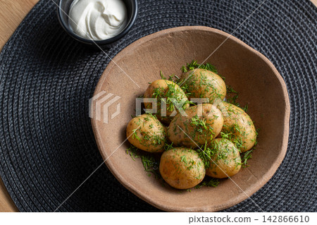 Baby potato with dill in clay bowl and sour cream angled Baby potato with dill in clay bowl and sour cream angled 142866610
