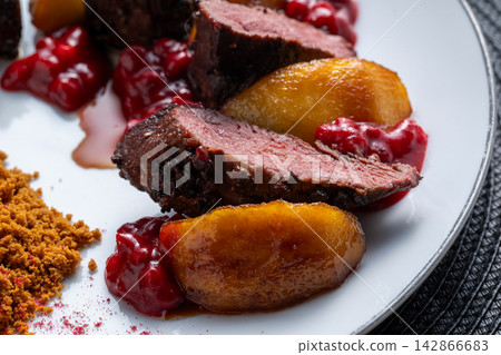 Sliced duck breast with pear and lingonberry side view 142866683