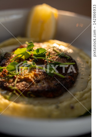 Pan fried meat cutlet on mashed potato side view warm light Pan fried meat cutlet on mashed potato side view warm light 142866933