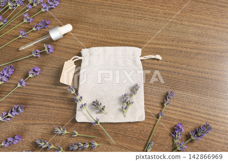 Lavender sachet bag mockup with cosmetic dropper pipette on wood. Natural herbal spa beauty product branding template with blank tag. Minimalist flat lay composition for organic wellness market trend. Lavender sachet bag mockup with cosmetic dropper pipette on wood. Natural herbal spa beauty product branding template with blank tag. Minimalist flat lay composition for organic wellness market trend. 142866969
