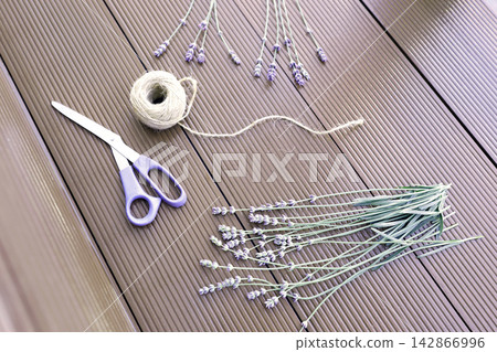 Lavender stems scissors twine ball on wooden background process of making bouquets. Dried organic lavender preparation workspace flat lay view composition. Handcraft hobby workspace with purple flower 142866996