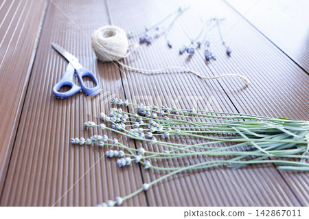 Lavender bouquet making process with fresh herbs violet scissors twine on brown wooden floor. Aesthetic organic workspace flat lay for handmade floristry crafting creation content. Modern rustic lifes Lavender bouquet making process with fresh herbs violet scissors twine on brown wooden floor. Aesthetic organic workspace flat lay for handmade floristry crafting creation content. Modern rustic lifes 142867011