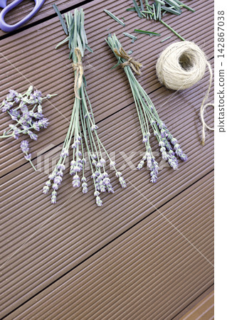 Lavender stems scissors twine ball on wooden background process of making bouquets. Dried organic lavender preparation workspace flat lay view composition. Handcraft hobby workspace with purple flower Lavender stems scissors twine ball on wooden background process of making bouquets. Dried organic lavender preparation workspace flat lay view composition. Handcraft hobby workspace with purple flower 142867038