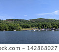 A yacht floating on the shores of Lake Windermere in the English Lake District, surrounded by a forest landscape. 142868027