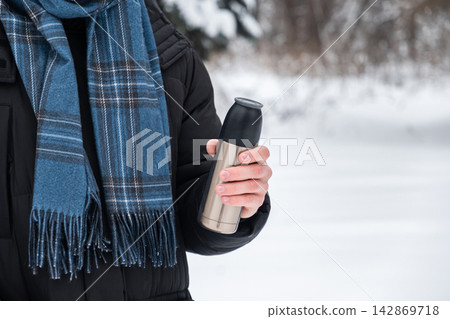 Young adult man holding thermos in winter park Young adult man holding thermos in winter park 142869718