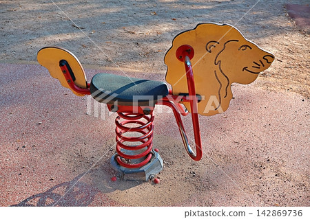 Empty lion spring rocker waits for young riders in sunlit playground. 142869736