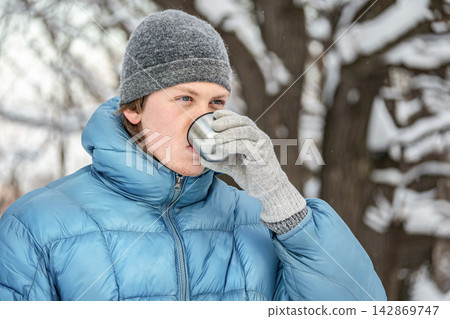 Man drinking hot beverage outdoors during winter Man drinking hot beverage outdoors during winter 142869747
