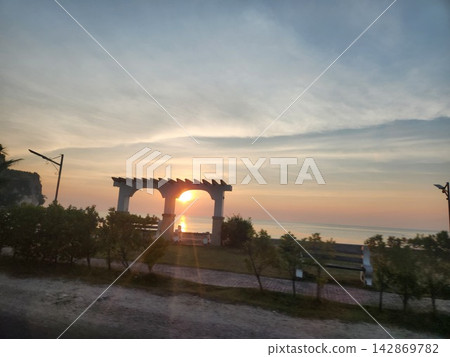 A beautiful sunset and calm sea viewed from behind a pergola. A beautiful sunset and calm sea viewed from behind a pergola. 142869782