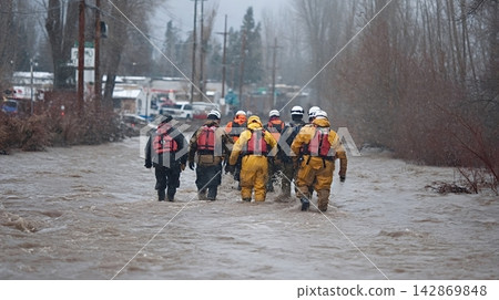 Rescue workers walking through dangerous flood water Rescue workers walking through dangerous flood water 142869848