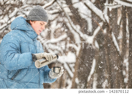 Man pouring hot drink from thermos outdoors in winter Man pouring hot drink from thermos outdoors in winter 142870112