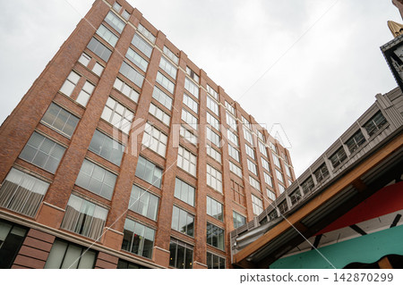 Low angle view of a tall brick office building with multiple windows in Manhattan, New York City. Urban architecture and modern city development create a classic downtown skyline atmosphere. 142870299