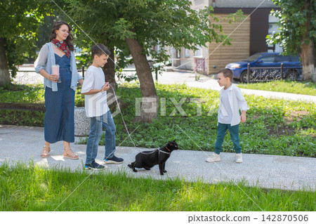 A woman and her two sons are walking a cat. A woman and her two sons are walking a cat. 142870506