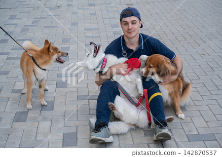 A man hugs his two dogs while on a walk. A man hugs his two dogs while on a walk. 142870537