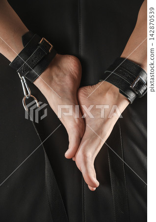 Women's legs in leather shackles. BDSM fetish. Women's legs in leather shackles. BDSM fetish. 142870539