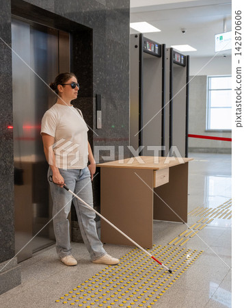 A blind woman exits an elevator. A blind woman exits an elevator. 142870606