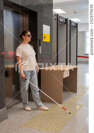 A blind woman exits an elevator. A blind woman exits an elevator. 142870636