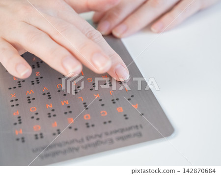 A blind woman learns the English alphabet from a braille sign. A blind woman learns the English alphabet from a braille sign. 142870684