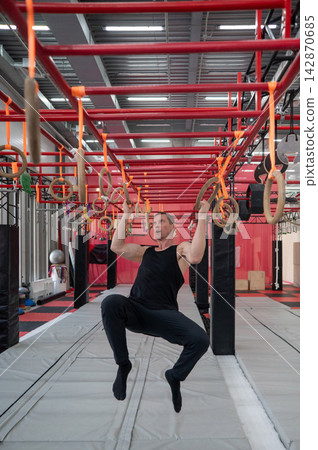 An athletic man practices at a ninja club's indoor obstacle course. An athletic man practices at a ninja club's indoor obstacle course. 142870685