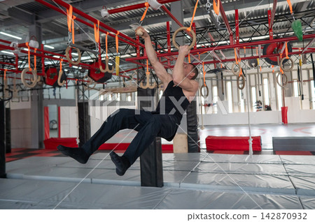 An athletic man practices at a ninja club's indoor obstacle course. An athletic man practices at a ninja club's indoor obstacle course. 142870932