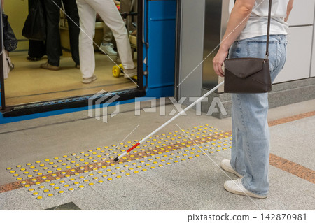 A blind woman enters a subway car. 142870981