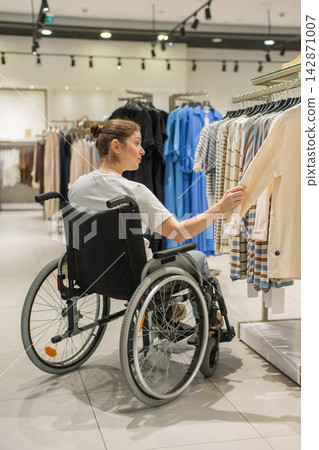 A Caucasian woman in a wheelchair shopping at a mall. A Caucasian woman in a wheelchair shopping at a mall. 142871007