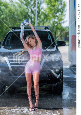 A Caucasian woman washes her car with a foam sponge. A Caucasian woman washes her car with a foam sponge. 142871036
