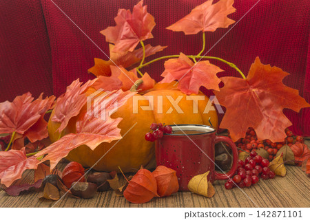 Autumn still life; mug of tea; orange squash and dry leaves on a wooden background 142871101