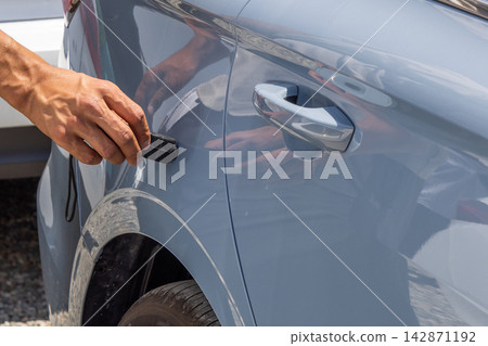 Adult Hand Touching Gray Car with Black Thickness Metering Device Adult Hand Touching Gray Car with Black Thickness Metering Device 142871192