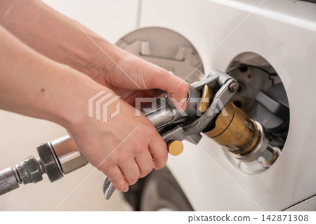 A woman fills a car with gas. Close-up of her hands. A woman fills a car with gas. Close-up of her hands. 142871308