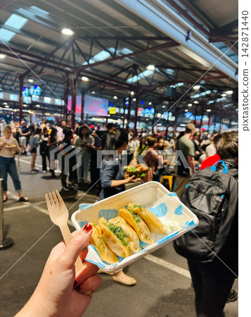 Woman holding pierogi dumplings at a busy night market Woman holding pierogi dumplings at a busy night market 142871440
