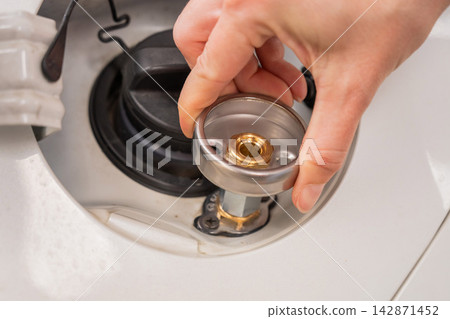 A woman installs an adapter on a gas tank in a car. 142871452