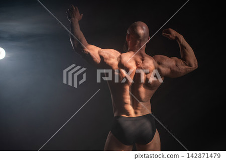 A male bodybuilder poses in shorts, showing off his back muscles. A male bodybuilder poses in shorts, showing off his back muscles. 142871479