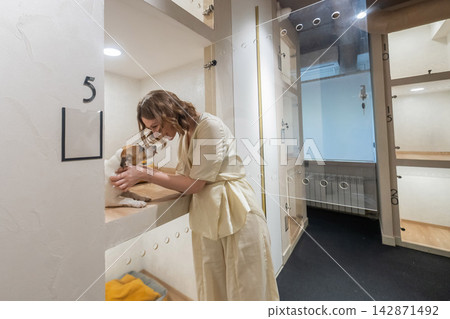 A Jack Russell Terrier at an animal shelter. A dog at an animal shelter in a cage with a glass door. A Jack Russell Terrier at an animal shelter. A dog at an animal shelter in a cage with a glass door. 142871492