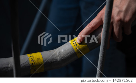 A blind woman reads the inscription on the railing of a staircase. A blind woman reads the inscription on the railing of a staircase. 142871562