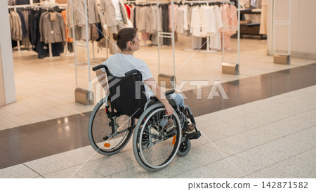 A Caucasian woman in a wheelchair shopping at a mall. A Caucasian woman in a wheelchair shopping at a mall. 142871582
