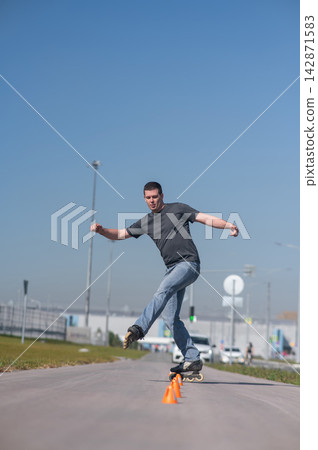 A Caucasian man rollerblades around the slalom course. 142871583