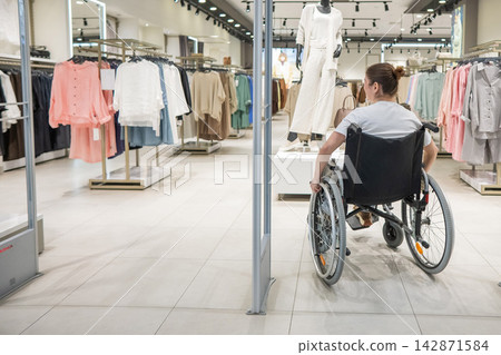 A Caucasian woman in a wheelchair shopping at a mall. A Caucasian woman in a wheelchair shopping at a mall. 142871584