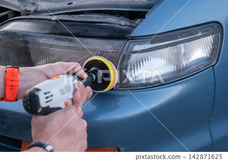 The process of polishing car headlights outdoors. The process of polishing car headlights outdoors. 142871625