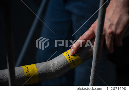 A blind woman reads the inscription on the railing of a staircase. A blind woman reads the inscription on the railing of a staircase. 142871698