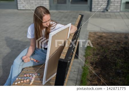 A Caucasian woman with mild cerebral palsy paints by numbers outdoors A Caucasian woman with mild cerebral palsy paints by numbers outdoors 142871775