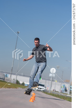A Caucasian man rollerblades around the slalom course. A Caucasian man rollerblades around the slalom course. 142871787